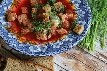 Traditional Ukrainian Borscht with Sour Cream. Red Beetroot Borscht with Dill, Bread, and Garlic on a Wooden Table.