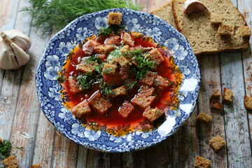 Traditional Ukrainian Borscht with Sour Cream. Red Beetroot Borscht with Dill, Bread, and Garlic on a Wooden Table.