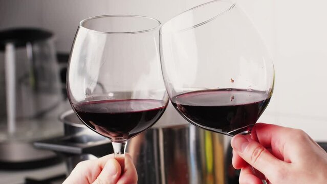 Cheers glasses of red wine, Romantic couple enjoying wine and cooking dinner at home, concept love, relationship and romantic, happy couple celebrating and making cheers with glasses of red wine