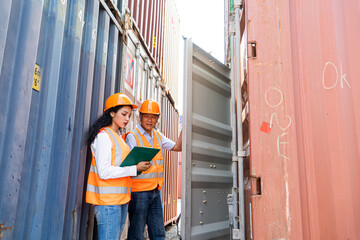 asian woman Engineer with note clipboard and asian man Supervisor in Hard Hats and Safety Vests Stand in Container Terminal. Container in export and import business and logistics.