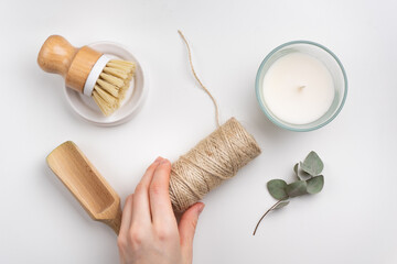 sustainable lifestyle concept flat lay with bamboo brush, wooden scoop, candle and hand holding the string.