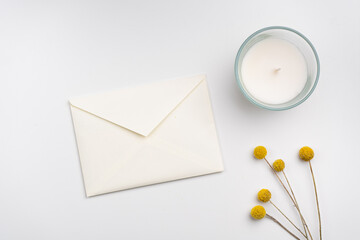 An envelope, candle and flowers on white background. Flat lay