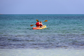 Kayaking in the sea, couple wearing life vests rowing with paddles in canoe. Man and woman in one team, travel and water sports