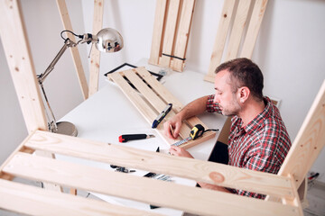 Obraz premium Man assembling new wooden shelf and furniture in the apartment.