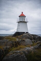 Fototapeta na wymiar Vertical shot of a lighthouse on the rocky coast on a cloudy day