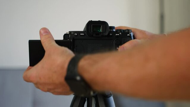 Man installing a professional camera on a tripod and opening the foldable display