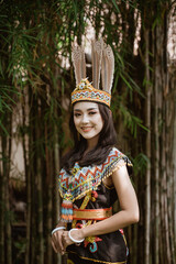 beautiful woman in king bibinge standing and put her hands in front of her body with the bamboos at the background