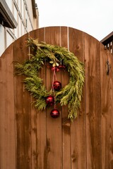Vertical shot of a Christmas decoration with red bulbs hanging on a wooden door