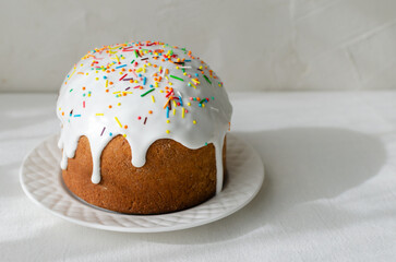 Traditional Ukrainian kulich on a white plate on a white tablecloth. The concept of festive Easter baking. Selective focus. Horizontal orientation. Copy space.