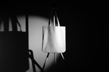 Tote Bag branding mockup template on a metal hanger with deep shadows, real photo. Blank isolated...
