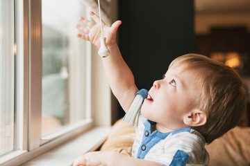 Curious Child Reaches For Window Blind Cord