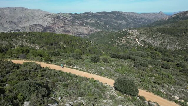Aerial footage of a female cyclist's epic gravel ride in the Spanish mountains.Gravel cycling adventure.Sport motivation drone video.female cyclist riding between the mountains.Castell de Castells.