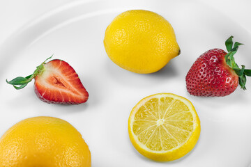 Fototapeta na wymiar Slices of lemon, strawberries on a porcelain plate