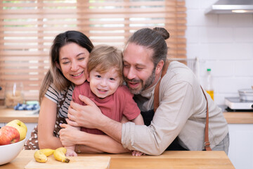 Fototapeta premium Mom and dad in the kitchen of the house with their small children. Have a good time making dinner together.