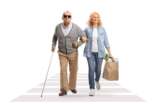 Woman Helping A Blind Senior Man With Grocery Bags Crossing A Street