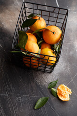 Sweet ripe mandarines in a basket on dark concrete background. Top view 
