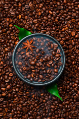 Roasted Arabica or Robusta coffee beans in a black bowl. Macro photo. Coffee background.
