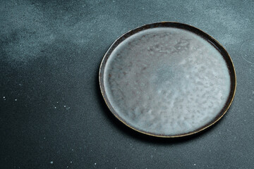 Black craft plate on dark stone table. Top view, copy space, Table setting. background for menu, layout, place for text , recipe background, food flat lay background