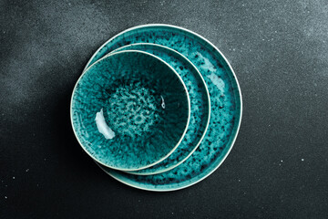 empty ceramic plate of delicate bed achuamarine turquoise color. Black background. The top is blowing. Go to sleep.