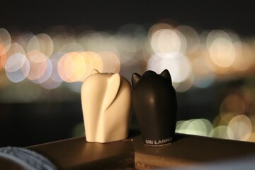 Selective focus of elephant figurines on a wooden surface with a background of blurred city lights