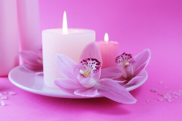 Fresh pink orchid flowers, burning candles, sea salt, on a bright pink background, spa concept, relaxation atmosphere, body care 