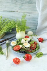 Salad of microgreens, lettuce, tomatoes, cheese and boiled eggs, on a plate, on the table, recipe from natural ingredients, healthy food