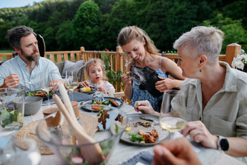Multigenerational family eating dinner at barbecue party.