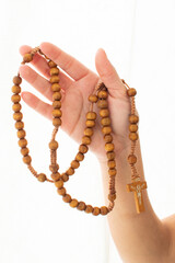 photograph of the hands of a girl showing a catholic rosary while raising a prayer, holy week belief