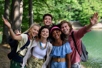 Group of young friends on camping trip near lake in summer.