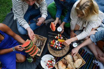 Group of multiracial young friends camping near lake and and having barbecue together, top view.