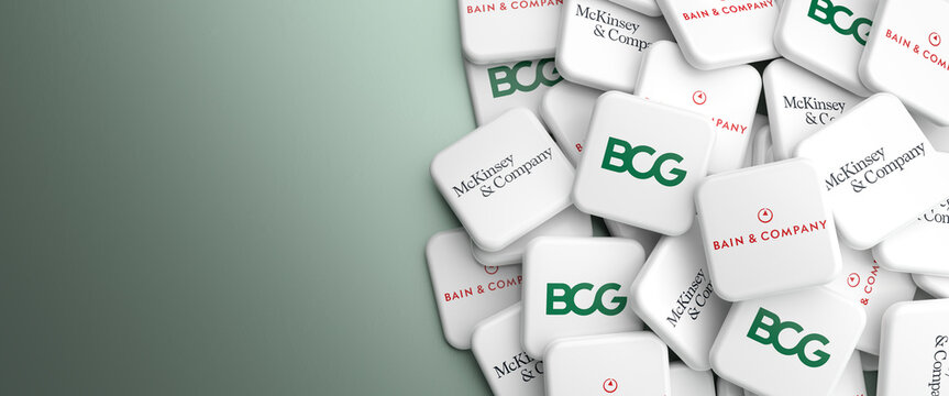 Logos of the Big Three management consulting companies Bain & Company, McKinsey & Company and Boston Consulting Group on a heap on a table. Web banner format with copy space