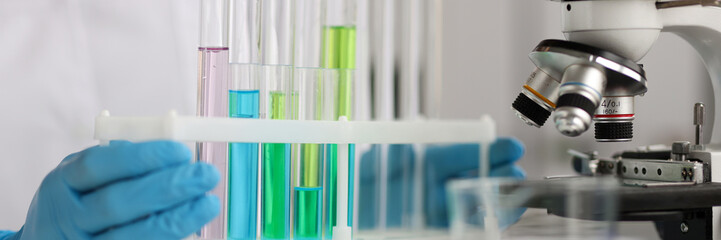 Scientist is holding test tubes with blue green liquids in laboratory