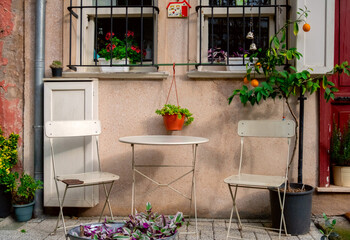 Table, chairs and potted plants on the balcony of an apartment building.