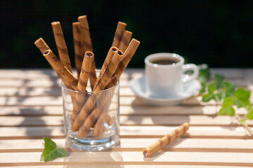 Sweet chocolate tubes with chocolate cream in a cup on the table