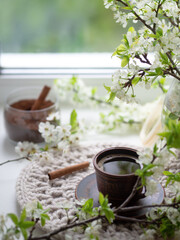 A cup of espresso on a velvet napkin by the window, spring time. Blossoming branches of white cherry