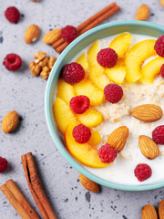 Healthy breakfast, milk oatmeal with raspberries, peach and almonds