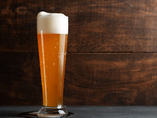 Glass of wheat german beer on wooden table