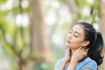 Fototapeta premium Asian woman stretching body and neck after jogging exercise at park in the city. Attractive athlete girl in sportswear enjoy outdoor lifestyle sport training fitness running workout in morning summer
