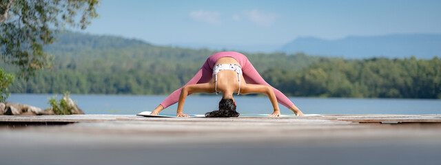 Beautiful attractive Asian woman practice fitness yoga pose on the pool above the Mountain peak in front of nature lake views, Feel so comfortable lifestyle and relax exercise in holiday morning