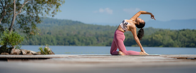 Beautiful attractive Asian woman practice fitness yoga pose on the pool above the Mountain peak in front of nature lake views, Feel so comfortable lifestyle and relax exercise in holiday morning