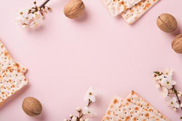 Passover celebration concept. Matzah, red kosher wine, walnut and spring beautiful branch of full bloom cherry or apple. Traditional Jewish bread on light pink background.  Pesach Jewish holiday.