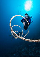 Divers swim over a coral reef near spiral coral.
