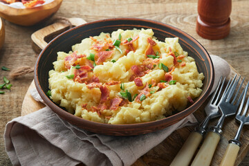 Mashed potatoes. Bacon mashed potatoes with green onion, pepper and cheddar cheese in bowl on old wooden backgrounds. Delicious creamy mashed potatoes. Top view.