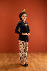 javanese woman in navy kebaya standing put her hands in front of her body on isolated background