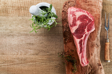 Fresh tomahawk raw steak. Dry aged raw tomahawk beef steak with herbs and salt on old wooden...