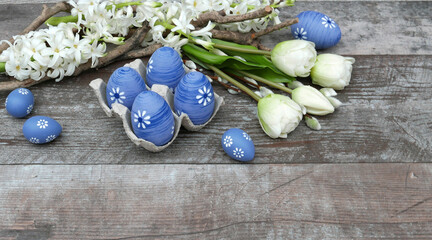Ostern Hintergrund: Blaue Ostereier mit einem Blumenarrangement, bestehend aus Tulpen und Hyazinthen, auf einem Hintergrund aus abgenutztem Holz.
