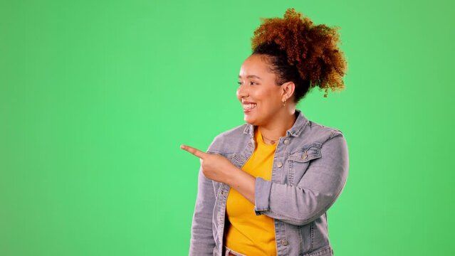 Happy woman pointing to green screen isolated on studio background for product placement, mockup or promotion. Young person or excited model face showing mock up chromakey space for gen z information