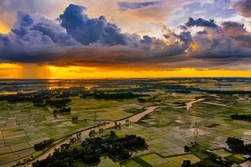 Aerial of a landscape with beautiful farmlands at sunset under the cloudy sky in Bangladesh