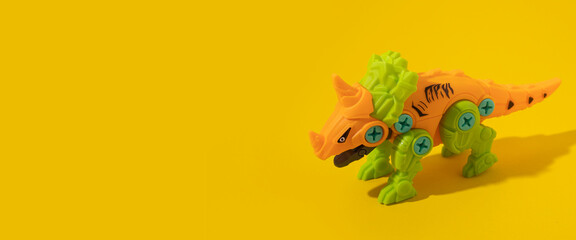 Fototapeta na wymiar Plastic dinosaur toy on yellow background. Banner