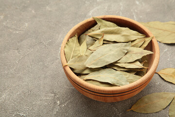 Bay leaves in wooden bawl on a concrete background.